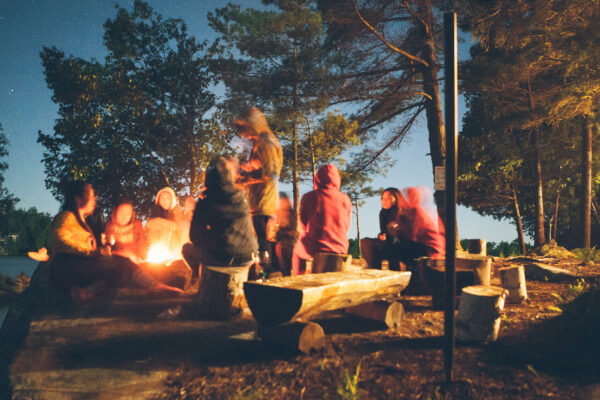 teenagers around a campfire at dusk