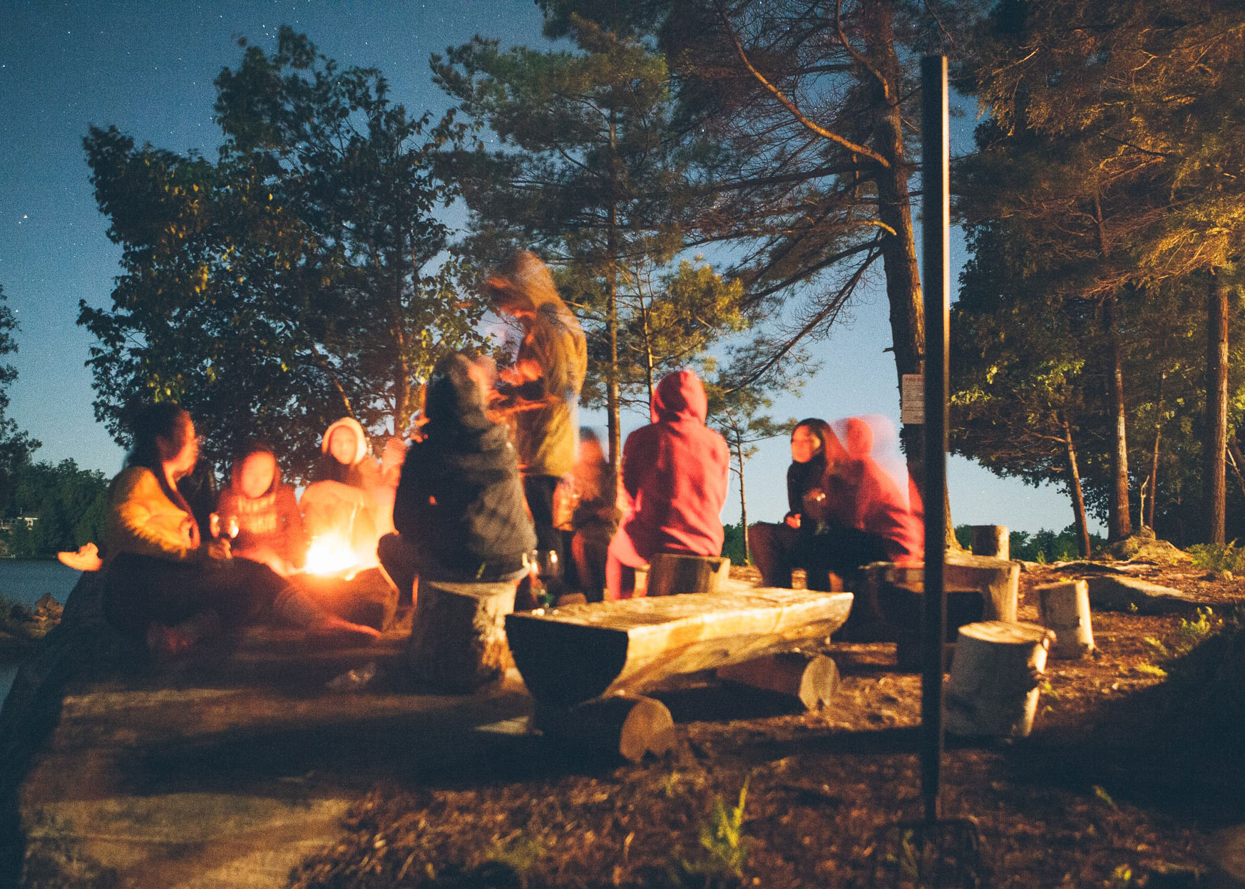 teenagers around a campfire at dusk