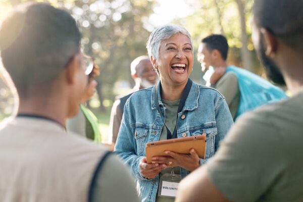 Woman holding clipboard talking to others while outside